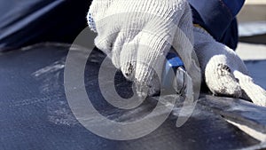 Close up for skilful worker hands cutting black rubber materal. Clip. Man wearing protective suit and gloves cutting a