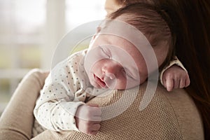 Close Up Of Sleeping Newborn Baby Sleeping On Mothers Shoulder