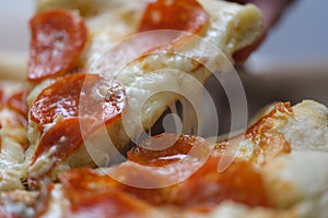 Close-up of a slice pizza with sausage and cheese rises up