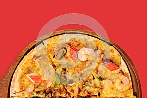 Close up slice of tasty hot baked seafood crispy pizza - mussels, shrimps and kani crab stick, chili pepper.