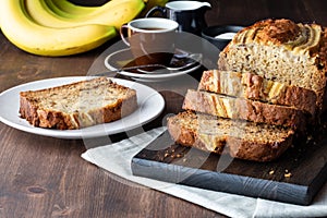 Close up of a sliced banana loaf with one slice on a small plate ready for eating.