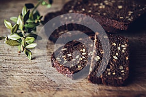 Close-up of the sliced brown bread at the cutting board on the wooden table with black background. Detailed close-up