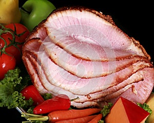 Close up of a sliced ham on a black background