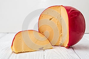 Close up. Sliced Head of Cheese Edam on white wooden background