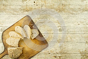 Close-up of a sliced loaf of homemade bread with sesame seeds on wooden cutting board on wooden table background