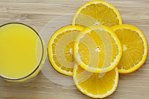 Close up of sliced orange and a full glass of orange juice on wooden surface