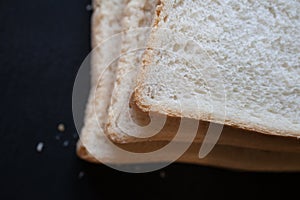 A close up of 3 slices of white bread against a black background photo