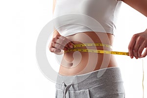 Close up of slim woman measuring her waist`s size with tape measure