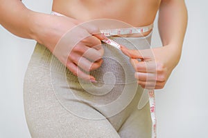 Close up of slim woman measuring her waist& x27;s size with tape measure. Isolated on white background.