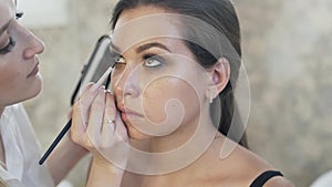 Close-up of slow motion, eye makeup, make-up artist asks the model to look up, picks up dark shadows on the brush and