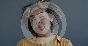 Close-up slow motion portrait of sleepy African American woman yawning and looking at camera on gray color background