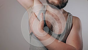Close up slow motion shoot of strong man in sweaty shirt showing biceps and touching hairy armpits. Refusal of depilation or shavi