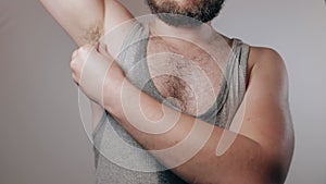 Close up slow motion shoot of strong man in sweaty shirt touching hairy armpits. Refusal of depilation or shaving. Beauty standard