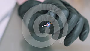 Close-up slow-motion shot of a dentist in a medical medical glove looks closely at the dental unit for the drill. Turns