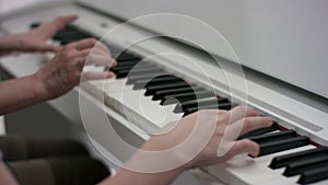 A close up slow motion showcase of hands of an adult and a child who are composing a tune on the piano at the same time