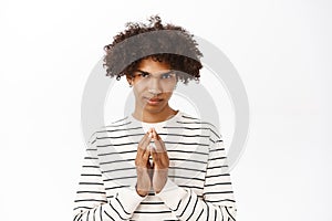 Close up of sly young man, scheming, has plan, steeple fingers and looking devious at camera, standing over white