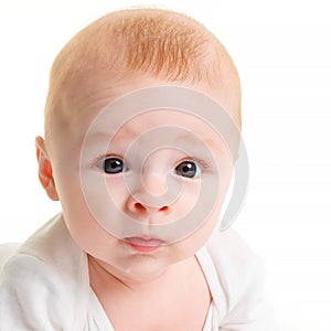Close-up of a small 4 month old baby on a white isolate and looking at the camera. Beautiful baby eyes
