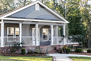 Close up of small blue gray mobile home with a front and side porch with white railing