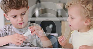 Close up of small boy, who puts the glue on the cutted from paper objects, during making applications with coloured