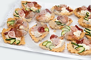 Close up of small canapes arranged on a plate over light background