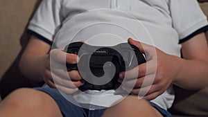 Close-up of a small child playing video games at home, he holds a joystick.