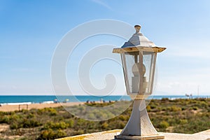 Close up of a small decorative lamppost on the exterior wall of a house near the beach photo