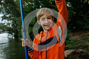 close-up of a small fish on a hook that the boy caught and holds in front of him