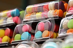 Close-up small French colorful macarons in glossy plastic container in franch restaurant