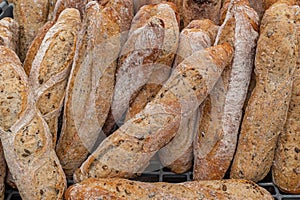 A close up of small freshly baked rustic baguettes for sale at a farmers market