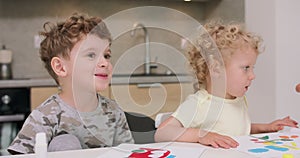 Close up of a small girl and a small boy sitting with their father at the kitchen table and are making applications with