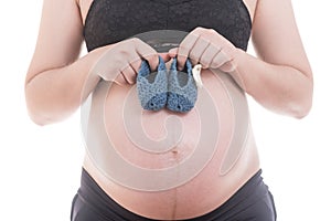 Close up Small shoes for the unborn baby in the belly of pregnant woman