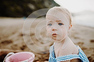 A close-up of small toddler girl on beach on summer holiday, playing.