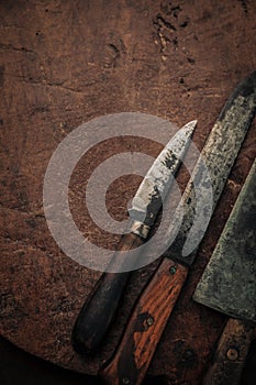 Close up of small utility knives on top of rustic old chopping board