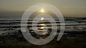 Close-up of small waves on background of sunset. Creative. Rolling small waves on seashore with sunset horizon. Waves on
