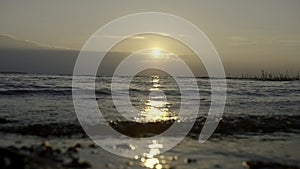 Close-up of small waves on background of sunset. Creative. Rolling small waves on seashore with sunset horizon. Waves on