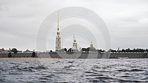 Close up of small waves of neva river and the golden spire of the Peter and Paul fortress. Action. Cloudy sky above the