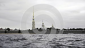 Close up of small waves of neva river and the golden spire of the Peter and Paul fortress. Action. Cloudy sky above the