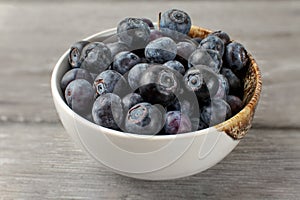 Close up on small white porcelain bowl full of blueberries.