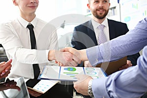 Close-up of smart colleagues smiling and shaking hand with prudent boss.