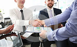 Close-up of smart colleagues smiling and shaking hand with prudent boss.