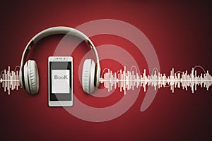 Close-up of smart phone, headphones and Audiobook on red background with Audio track. Audio, listen. Audiobook concept photo