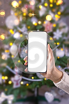 Close up smartphone with empty screen mockup on holiday background with Christmas tree