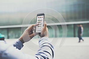 Close-up of smartphone with graphs, diagrams and charts on screen in male hands.