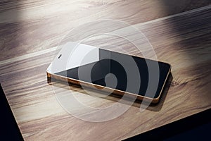 Close up of smartphone screen with reflections on wooden table.