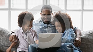 Close up smiling African American father with kids using laptop