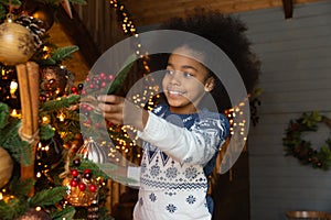 Close up smiling African American little girl decorating Christmas tree