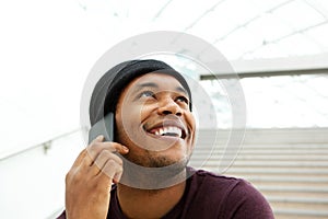 Close up smiling african american man talking with cellphone and looking up
