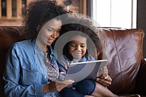 Close up smiling African American mother with daughter using tablet