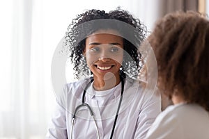 Close up smiling African American pediatrician doctor listening to patient