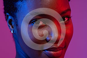 Close up of smiling african american woman with short hair in blue and red light